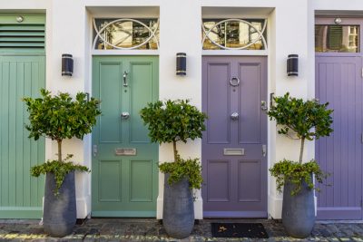 Two residential properties, one with a green front door and one with a purple front door